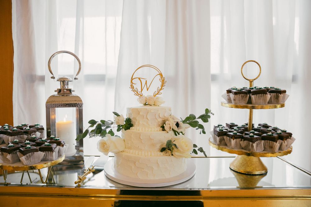 Elegant white wedding cake display with floral decorations and golden accents.