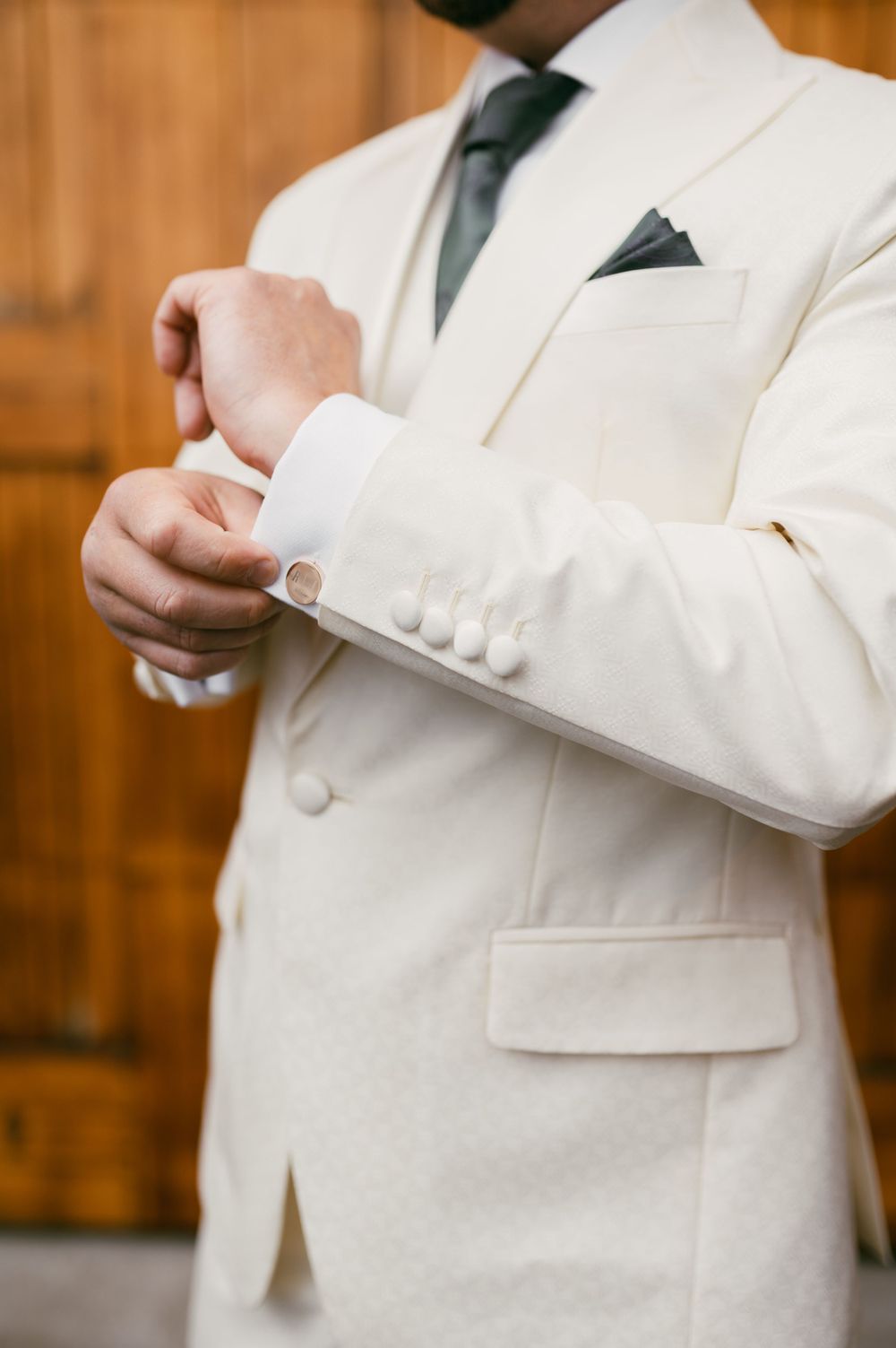 Close-up details of a white formal suit jacket being adjusted and buttoned.