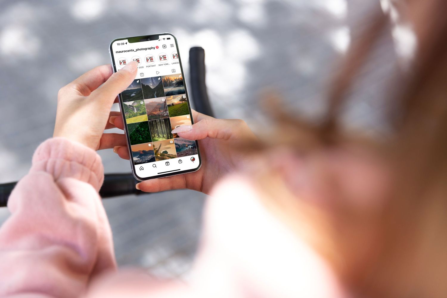 Hand holding smartphone displaying social media feed against blurred background.