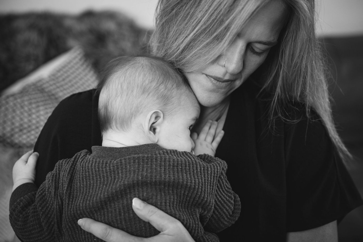 Intimate black and white moment showing gentle embrace between caregiver and infant.