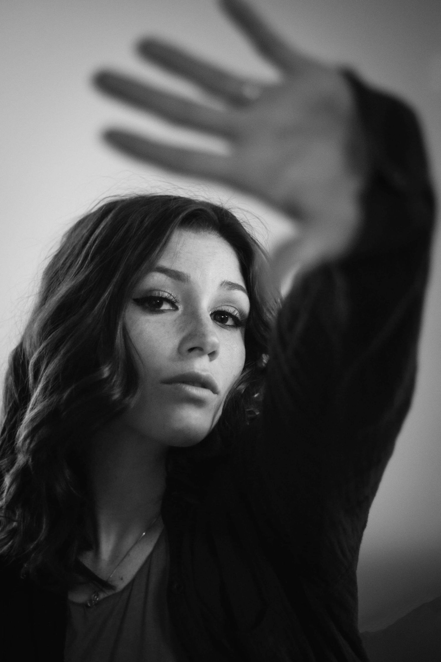 Dramatic black and white portrait with raised hand creating shadow effect.