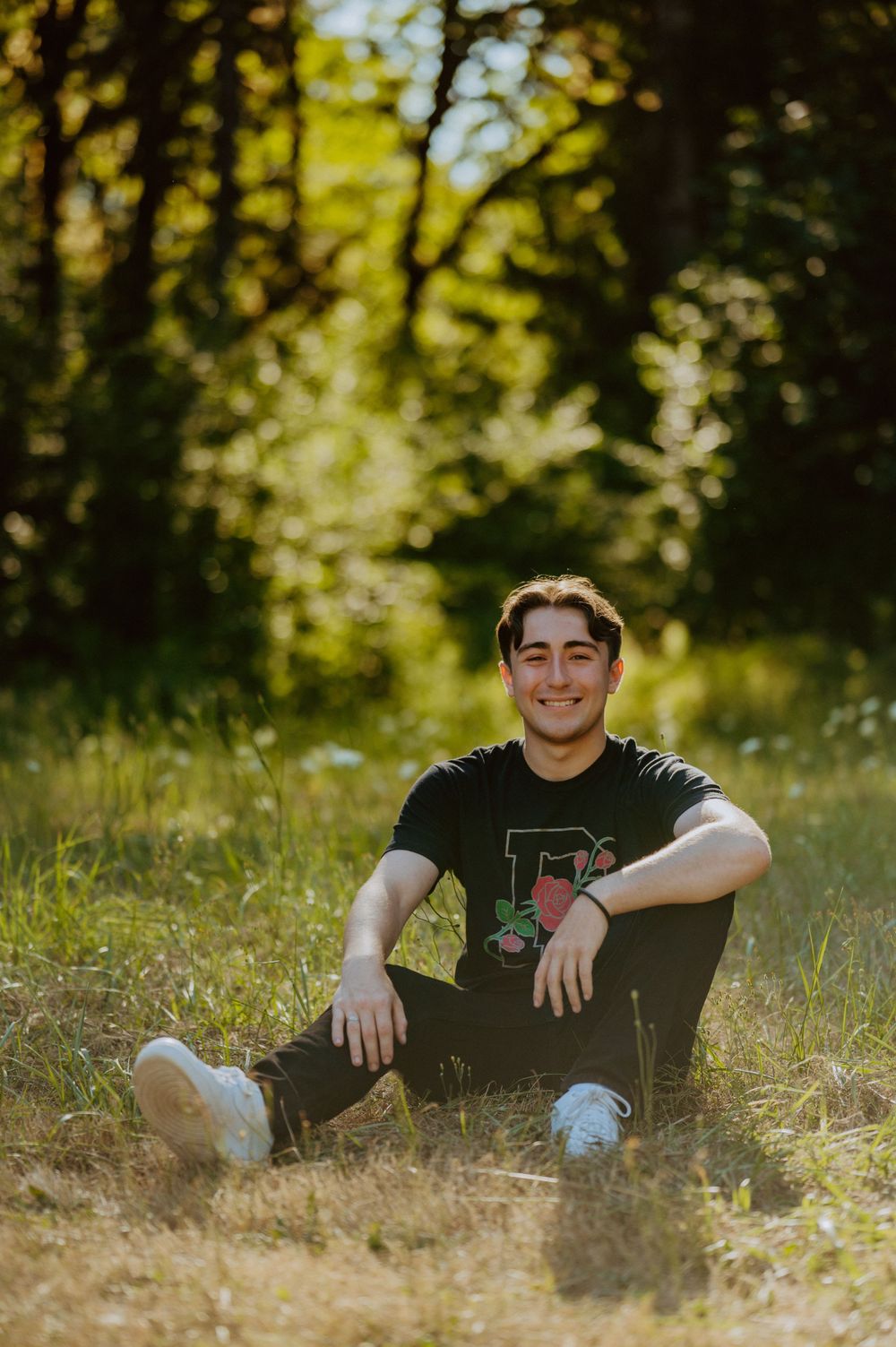 Person relaxing on grass in a sunny outdoor setting wearing casual attire.