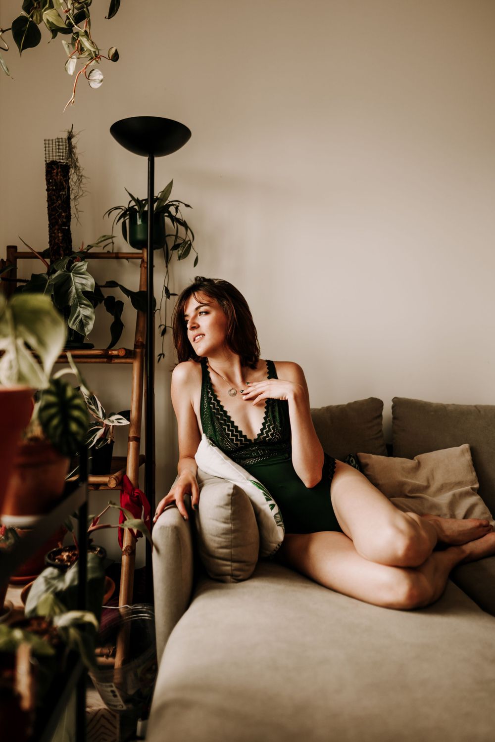 Indoor portrait with houseplants showing figure lounging on beige couch.