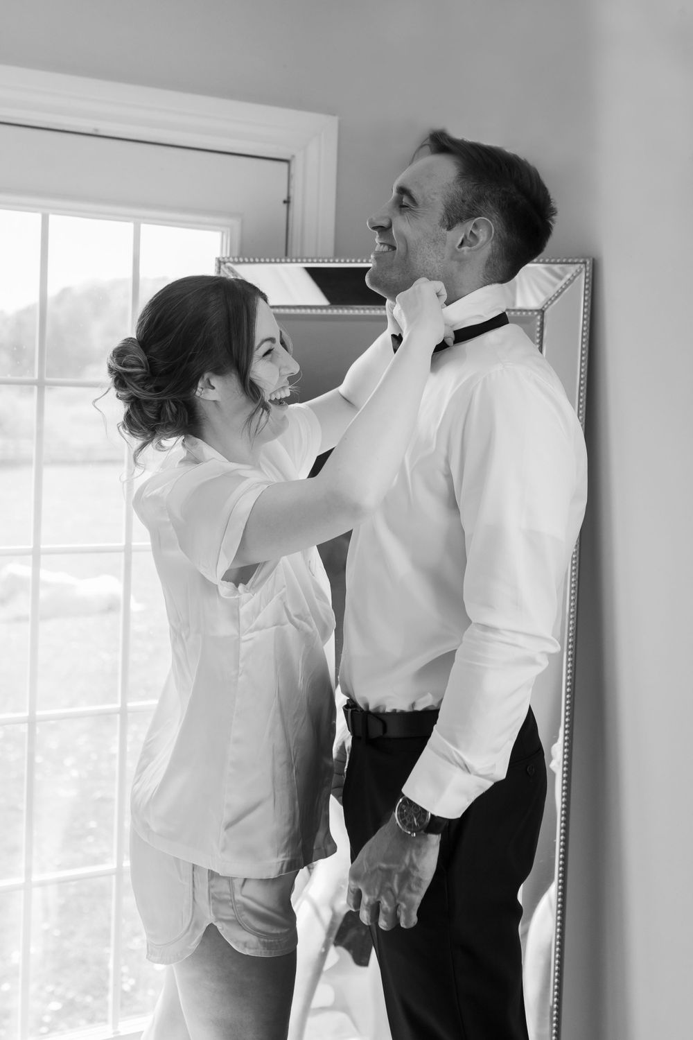 Groomsmen getting ready in white shirts and black pants before a wedding.