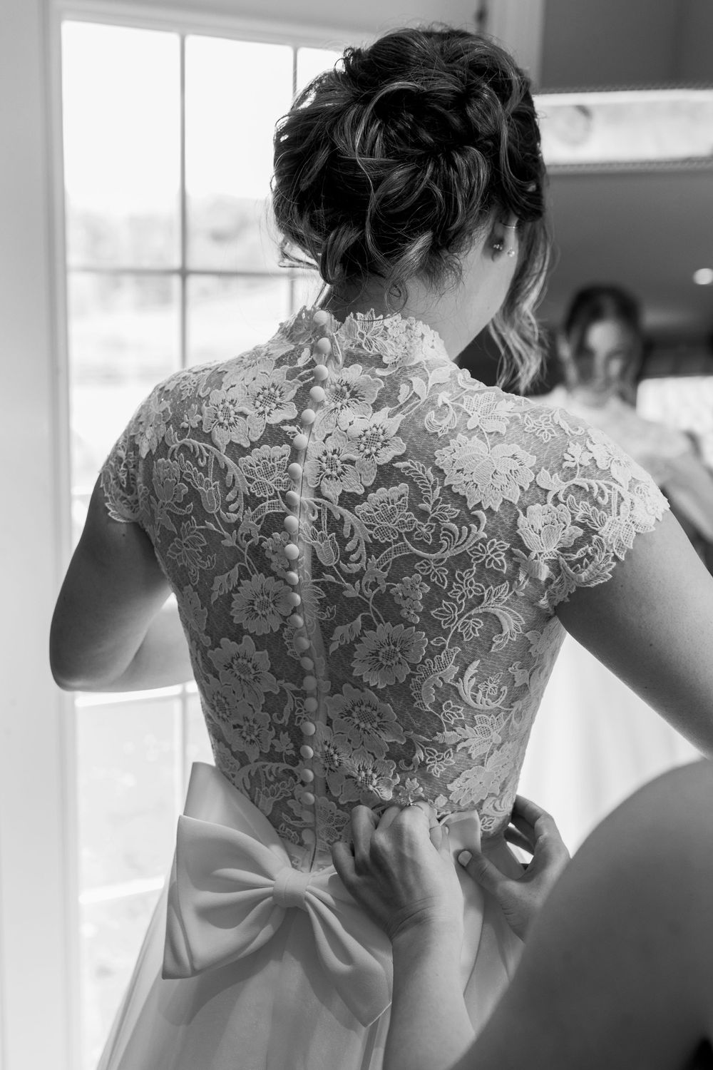 Close-up details of an elegant lace wedding dress back with delicate bow accent.