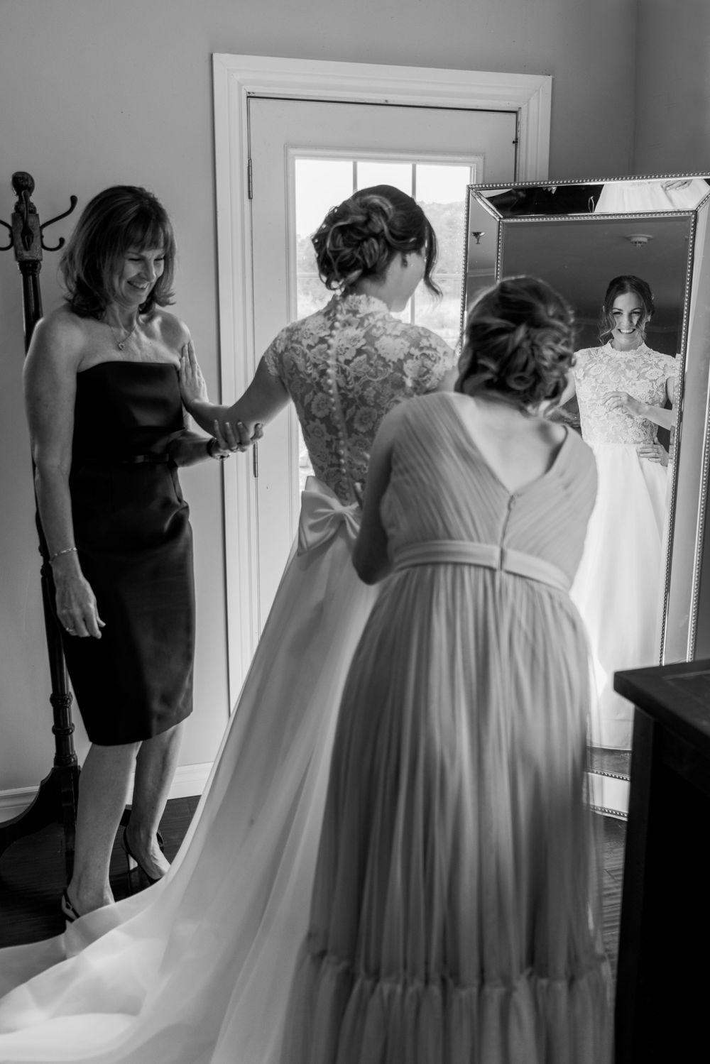 Getting ready scene showing the intricate details of a wedding dress being fitted.