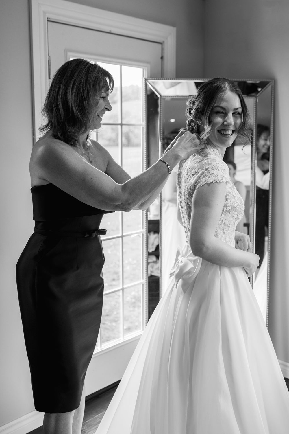 Black and white photos showing the process of getting dressed in a wedding gown.