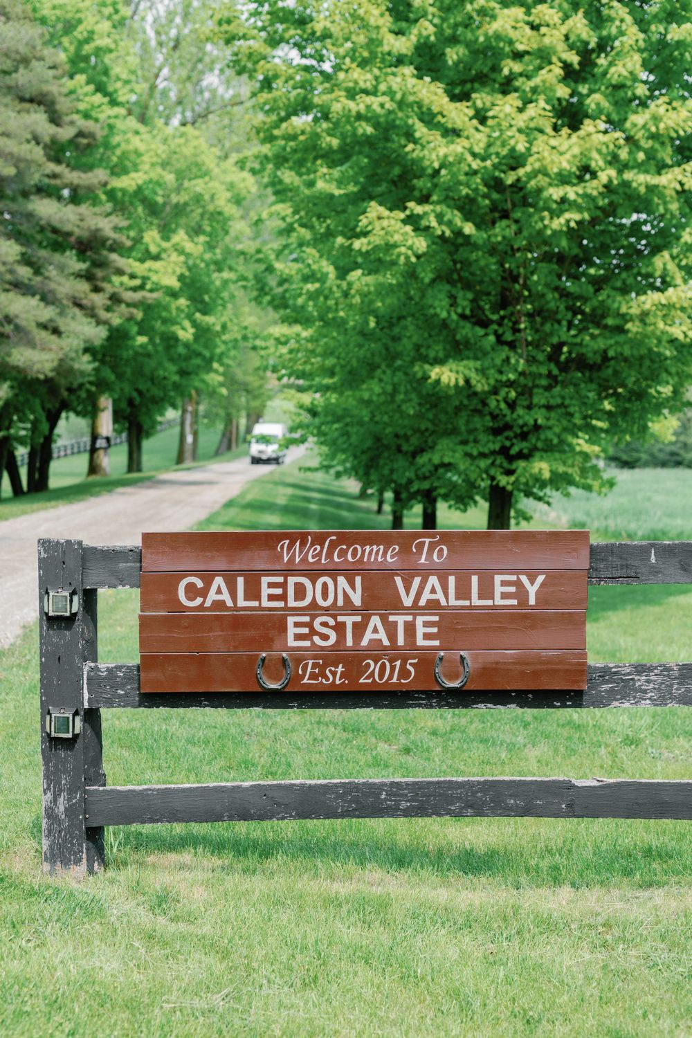 Wooden entrance sign for Caledon Valley Estate established in 2015 surrounded by lush green trees and grass.