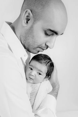 Intimate black and white portrait of parent and baby in tender embrace.