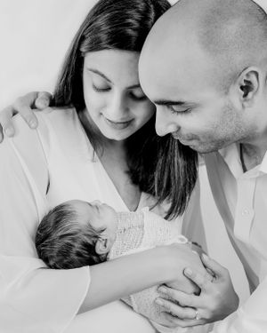 Black and white portrait of family sharing tender moment with newborn baby.