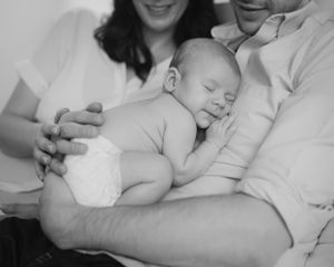 Family lying together on white bedding in casual intimate moment.