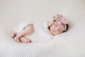 Minimalist newborn photography against white textured backdrop.