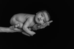 Artistic black and white newborn photography series on dark background.