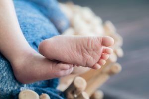 Close-up of newborn baby feet against blue and cream textured background.