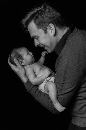 Black and white portrait of father and baby sharing tender moment.