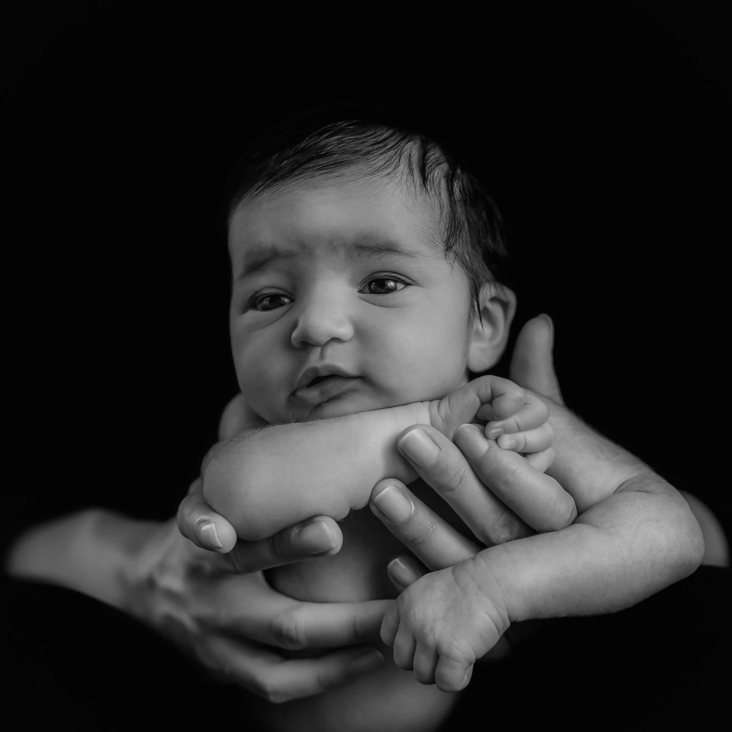 Close-up black and white portraits of an infant with dramatic lighting.