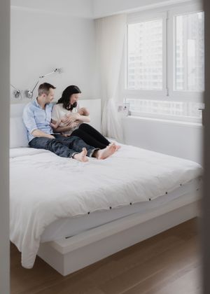Family relaxing together on white platform bed in minimalist room.