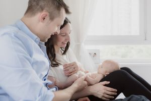 Candid family lifestyle session on white bed with natural window light.