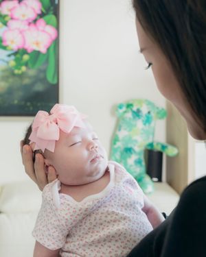 Baby with pink bow sleeping peacefully while being cradled.