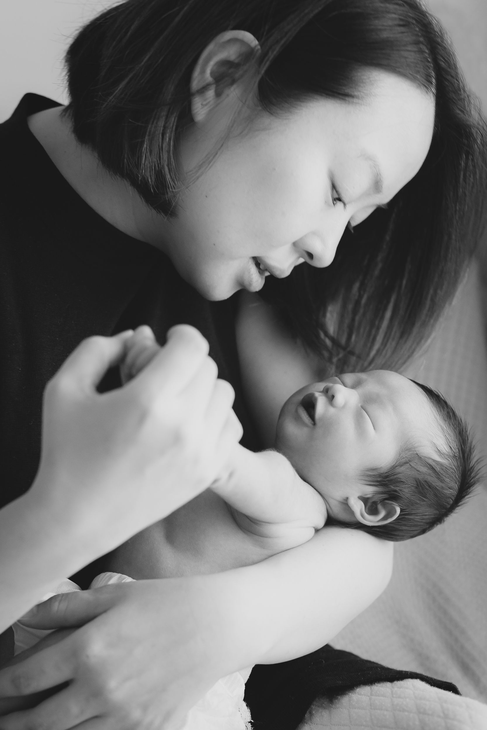 Black and white photo of intimate bonding moment between parent and newborn.