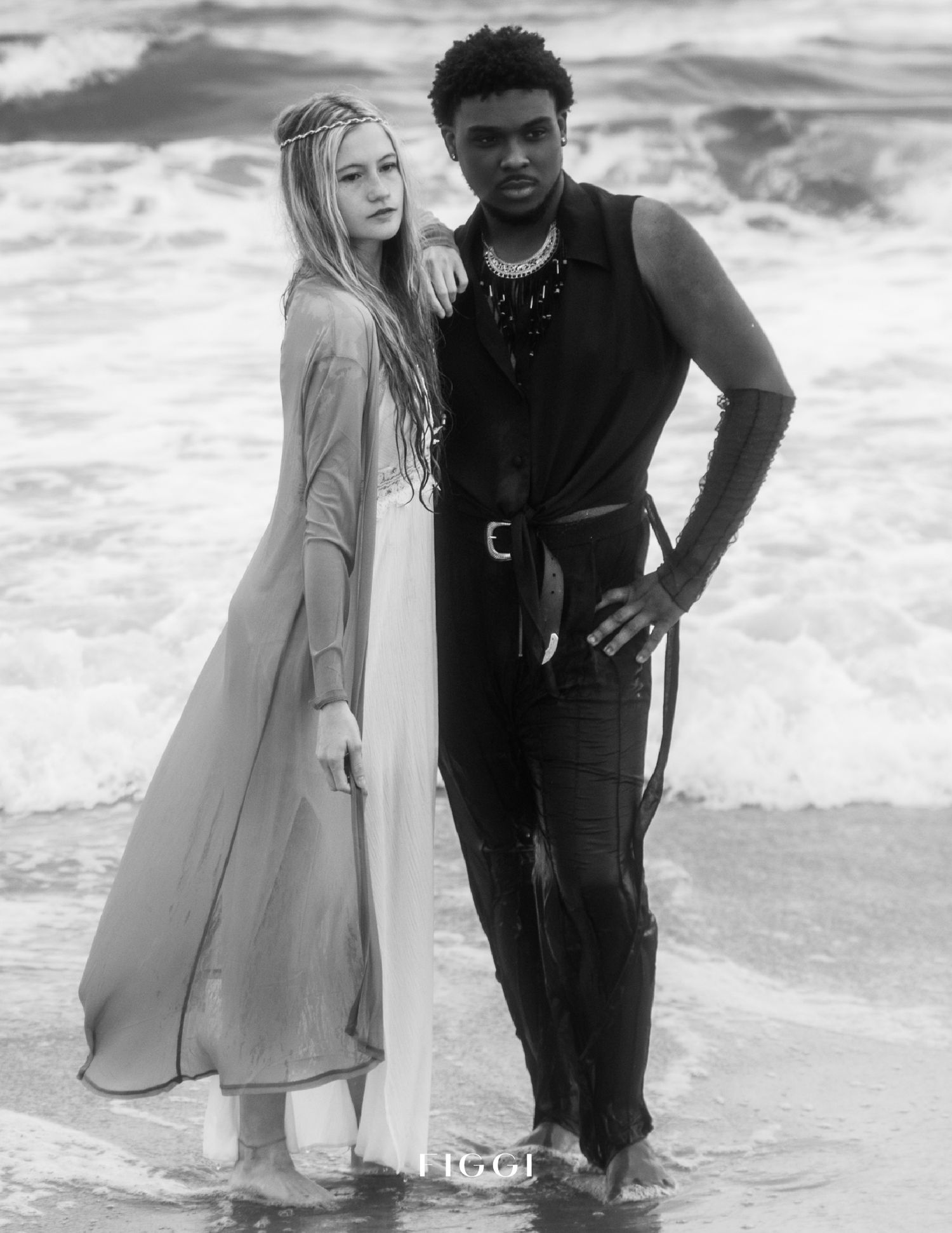 Black and white beach portrait with waves crashing in background.