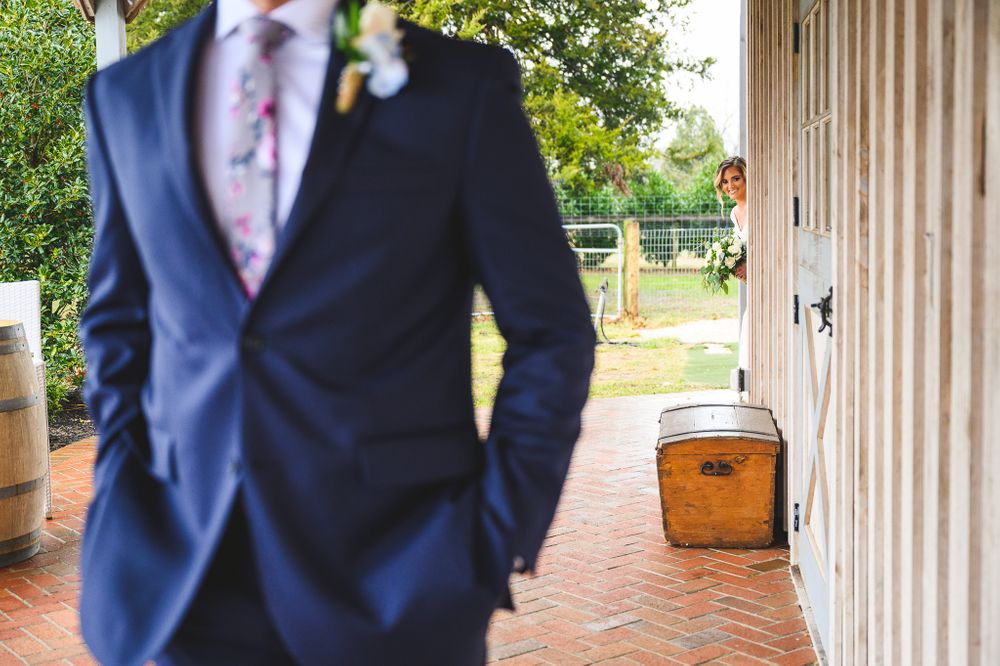 bride peeking out at groom during the first look