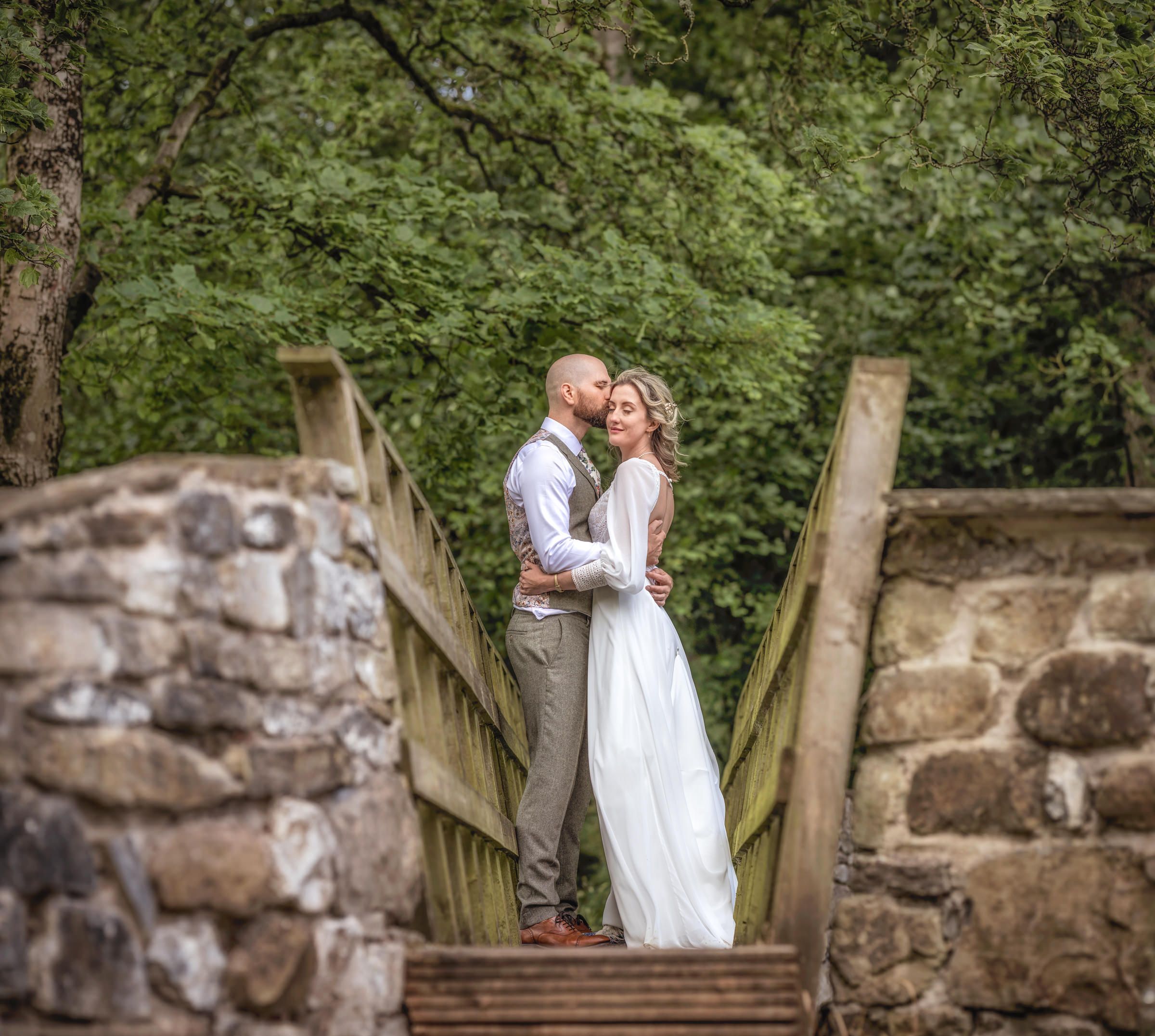 Artistic wedding portrait captured on stone and wooden bridge.