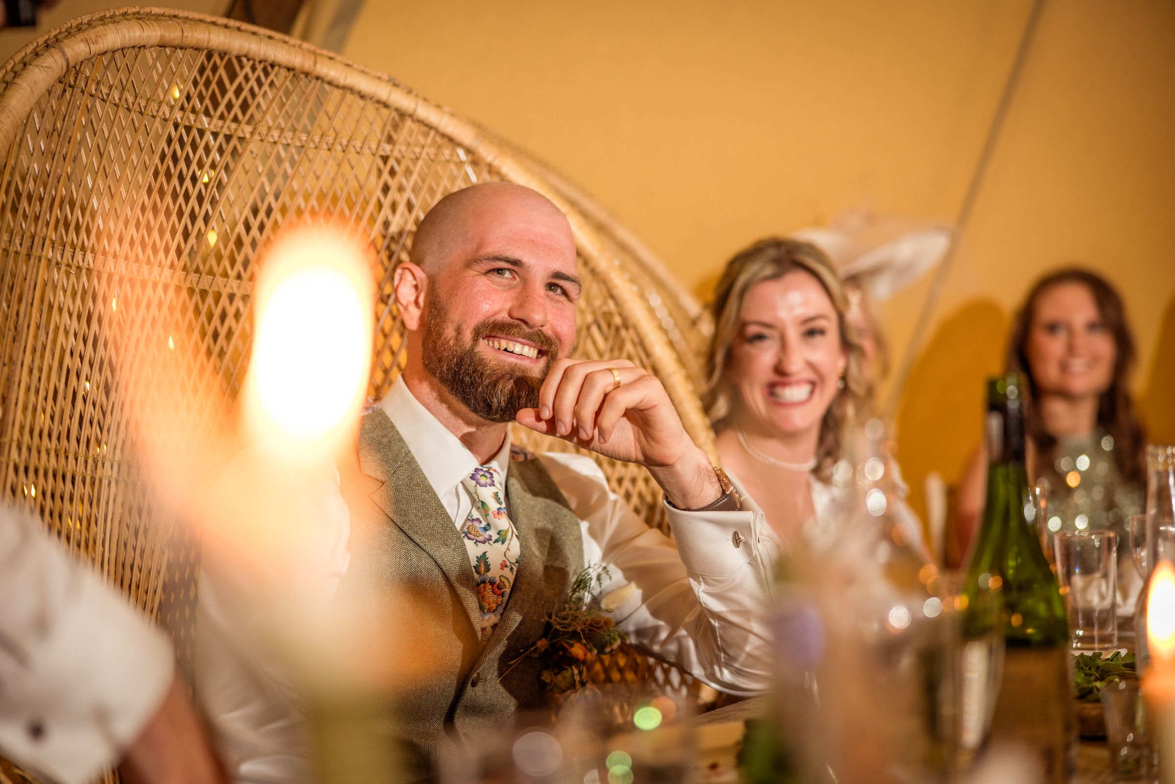 Candlelit wedding reception scene with vintage peacock chair and warm lighting.