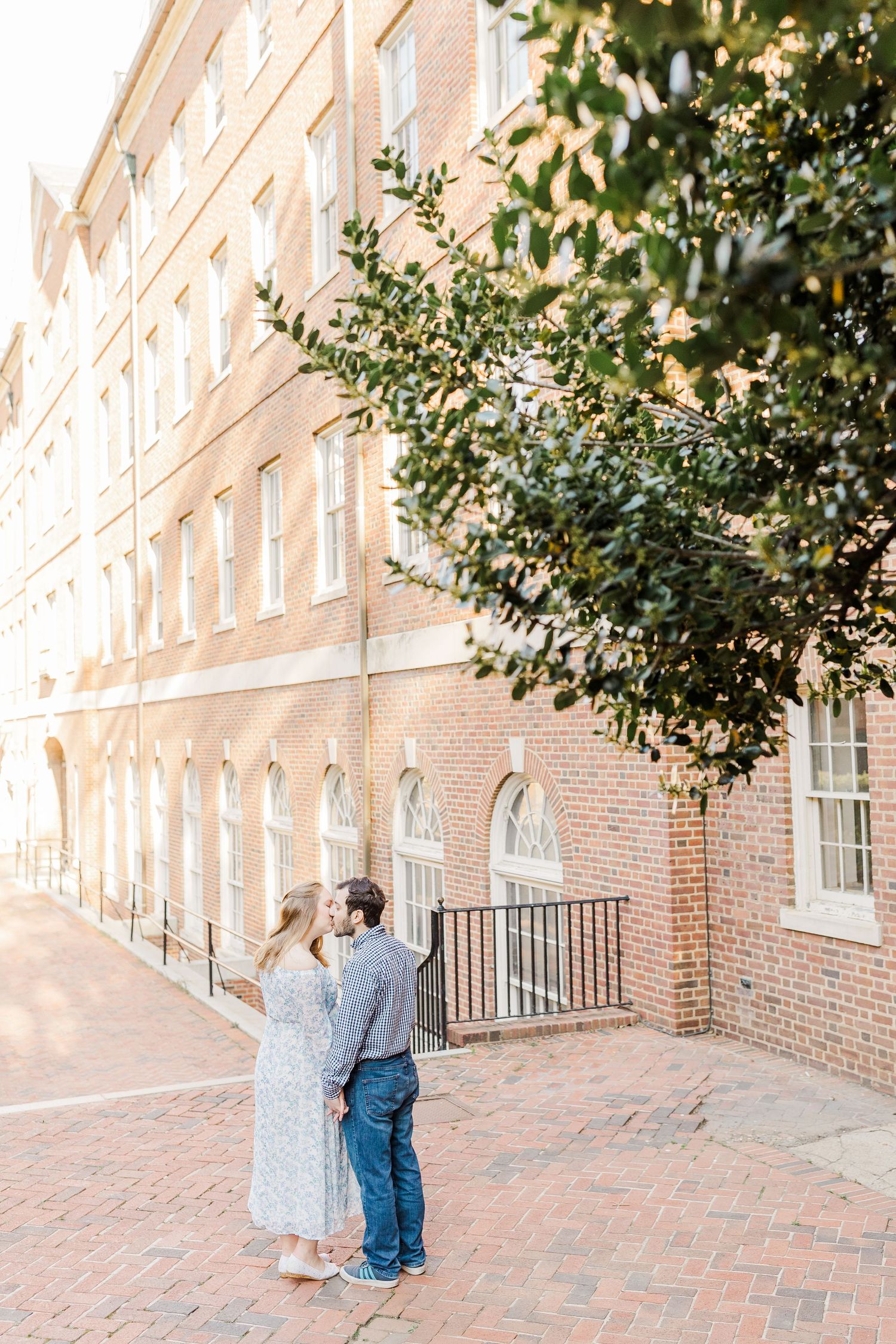 A romantic moment captured against a historic brick building with elegant architecture.