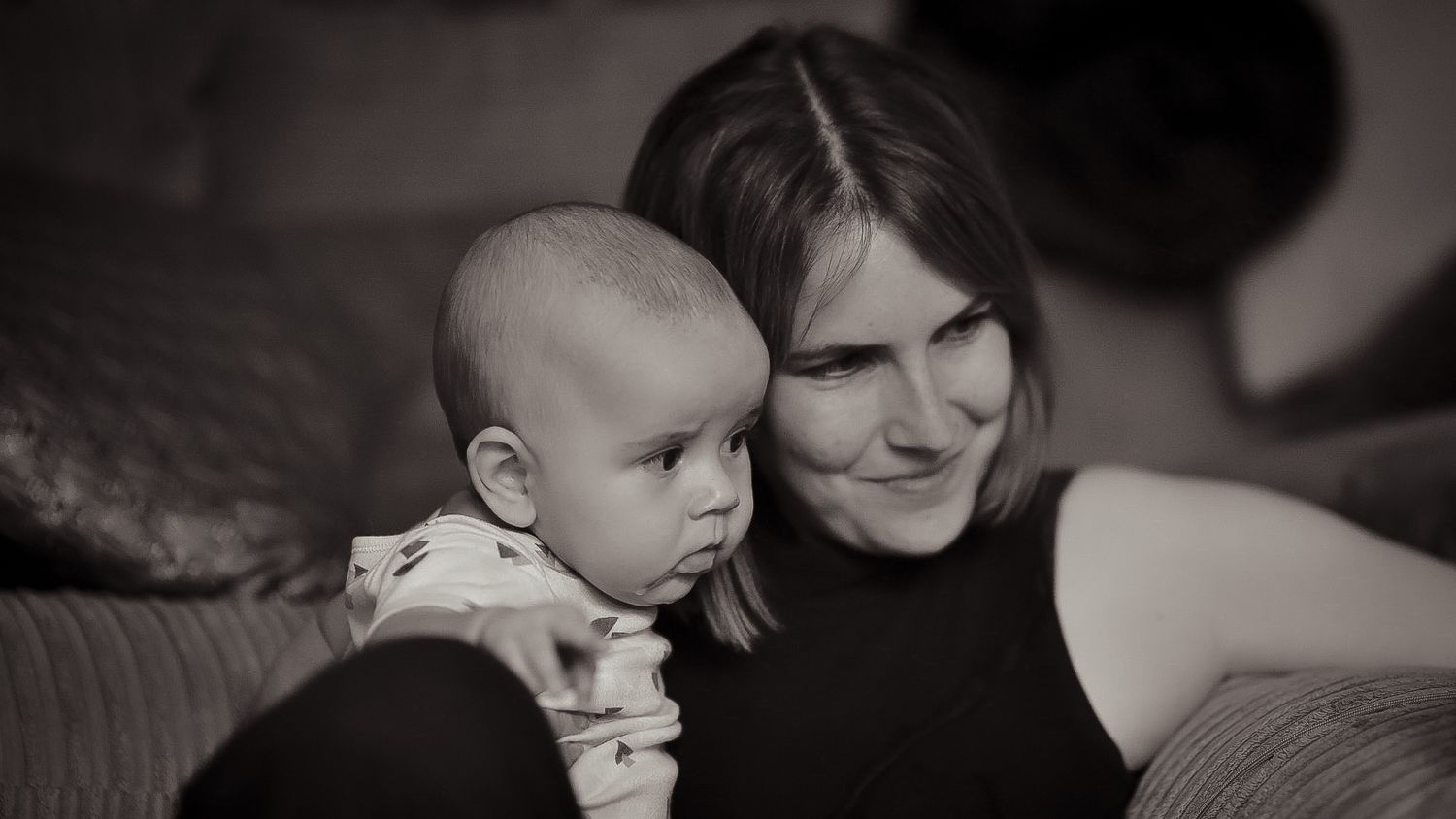 mum holding baby in her lap looking at something together