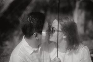 Couple kissing one another while holding an umbrella