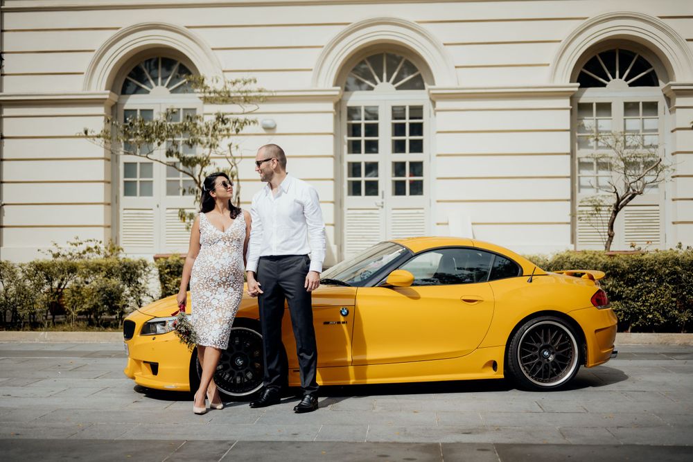 Couple posing with their car infront of a colonial building