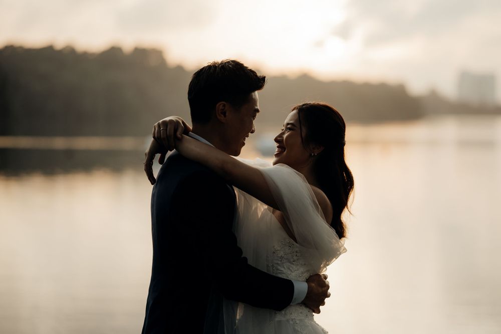 Couple hugging one another with the sun peaking from the trees