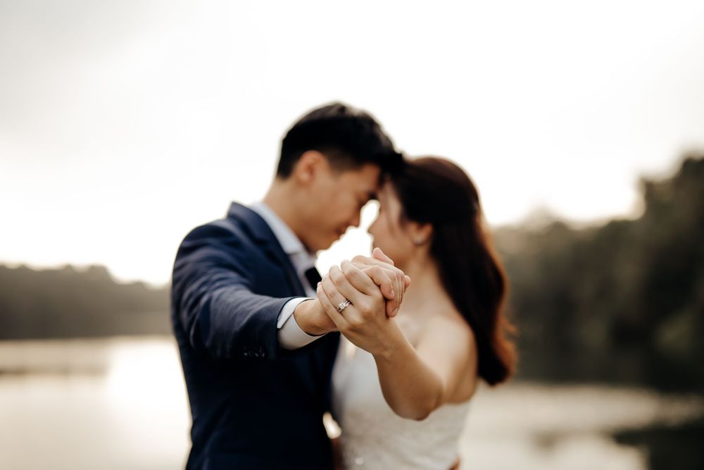 Couple showing off their ring with a nice sunset at the back