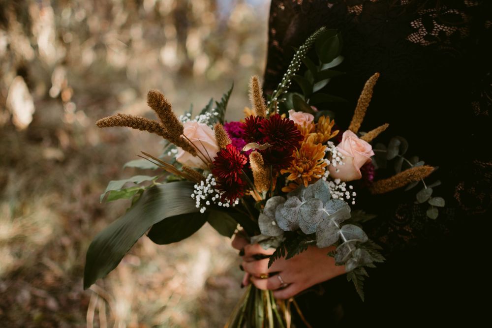 Vibrant autumn bouquet with pink flowers and eucalyptus leaves in natural lighting.