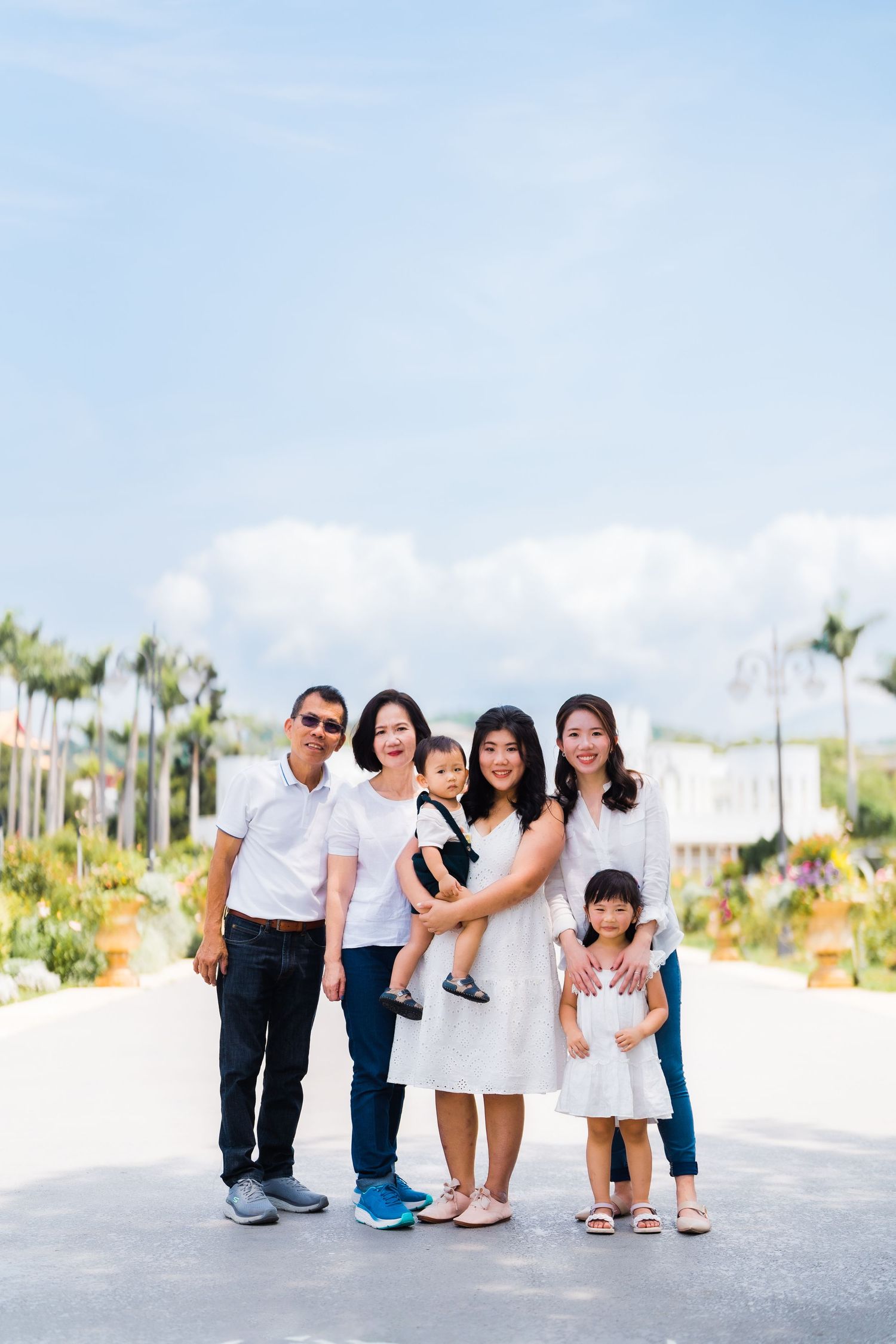 A cheerful family group standing together on a sunny day with palm trees in the background.