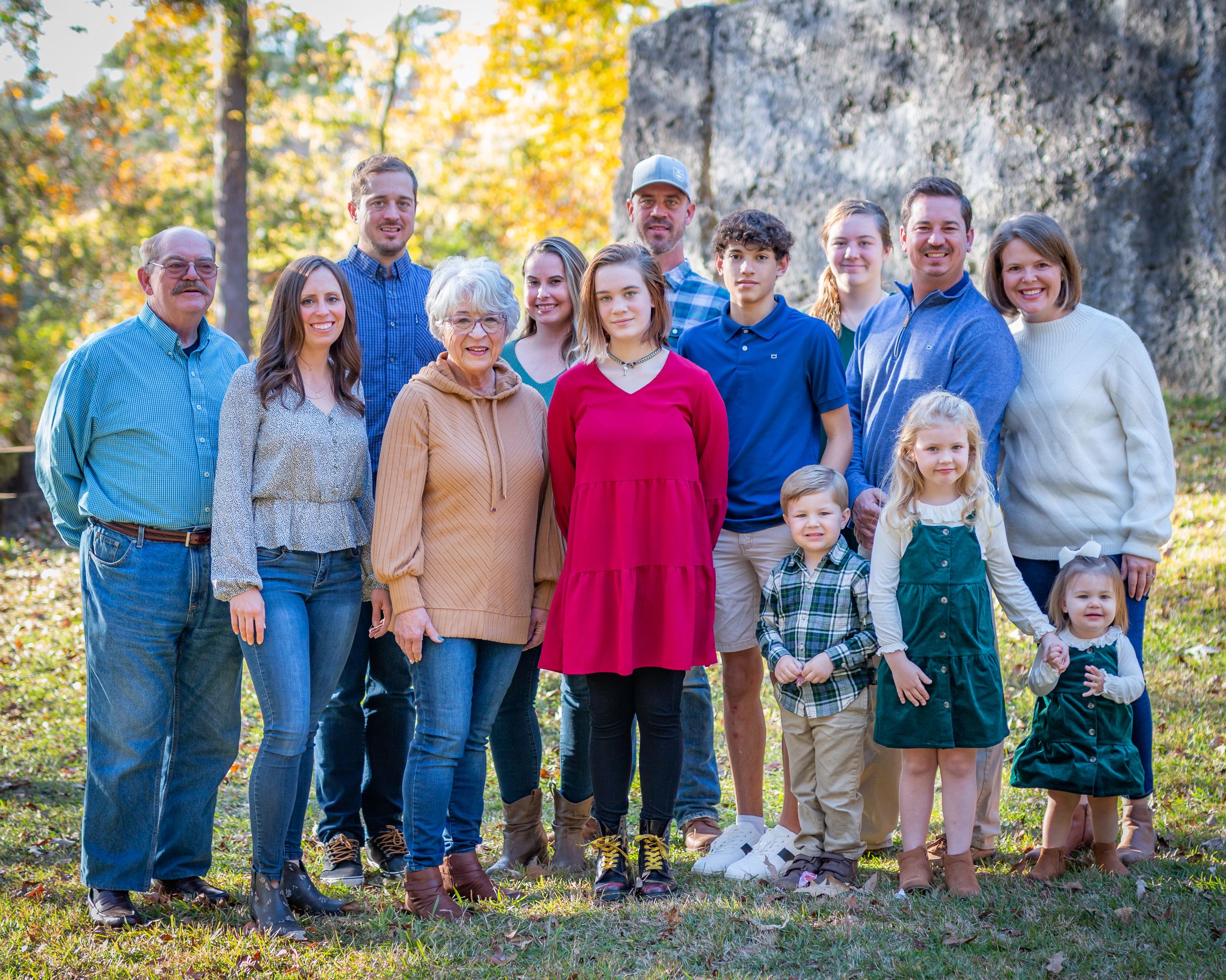 Extended family portrait outdoors with fall foliage in the background.