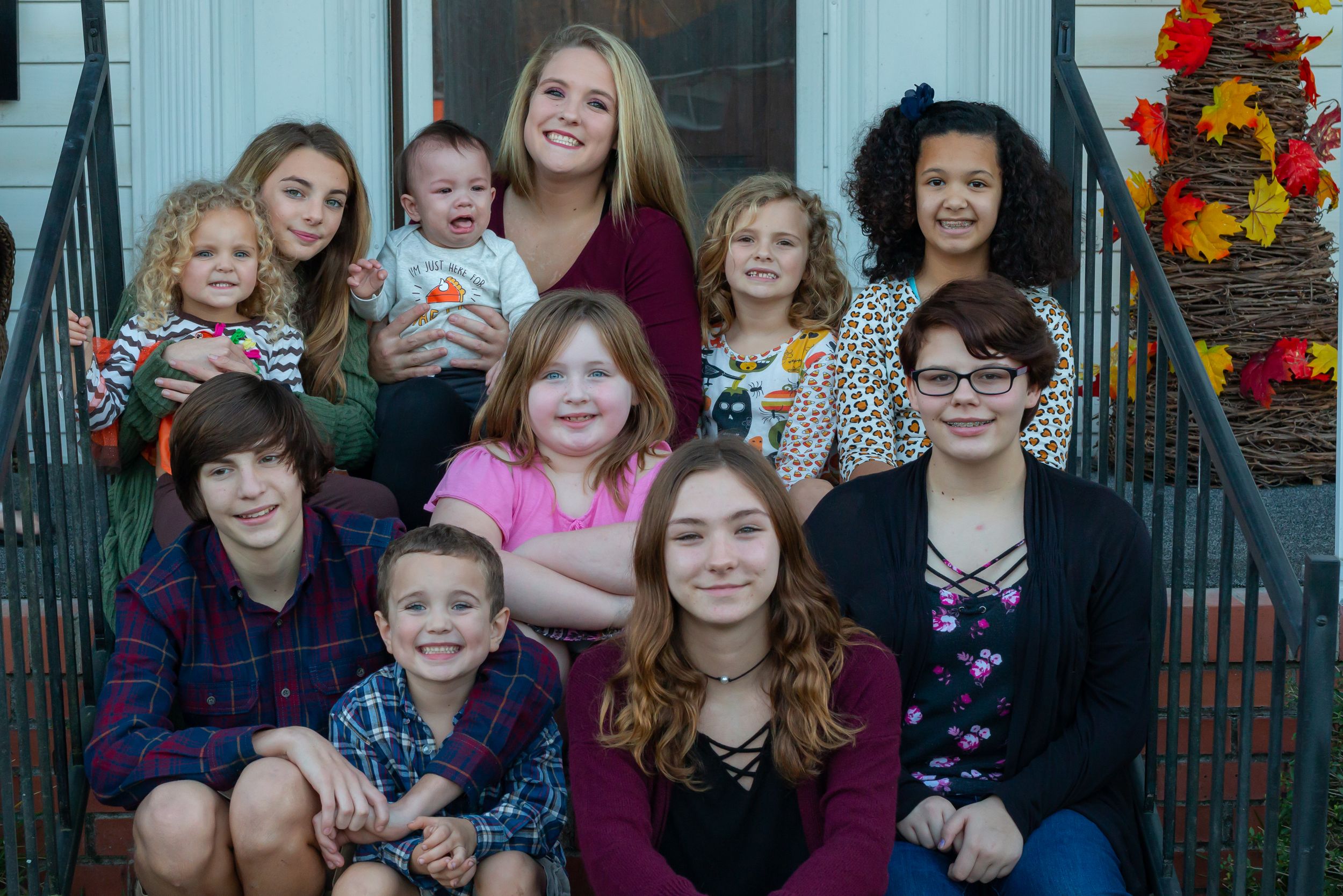 Group portrait of family members gathered on steps with autumn decorations.
