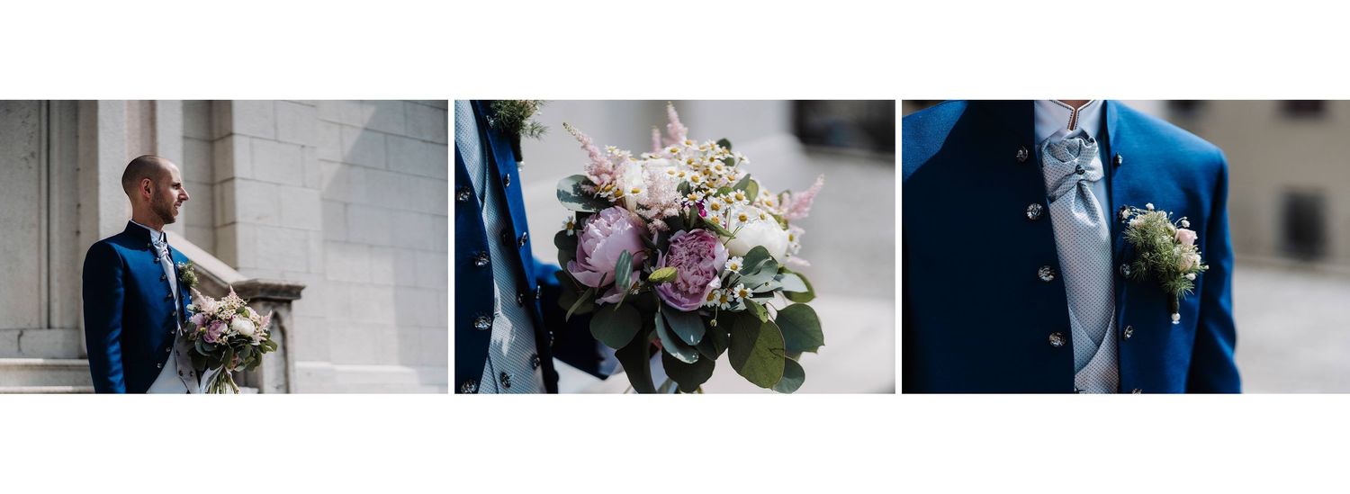Elegant groom in royal blue suit holding soft pink and white bridal bouquet outside stone building.