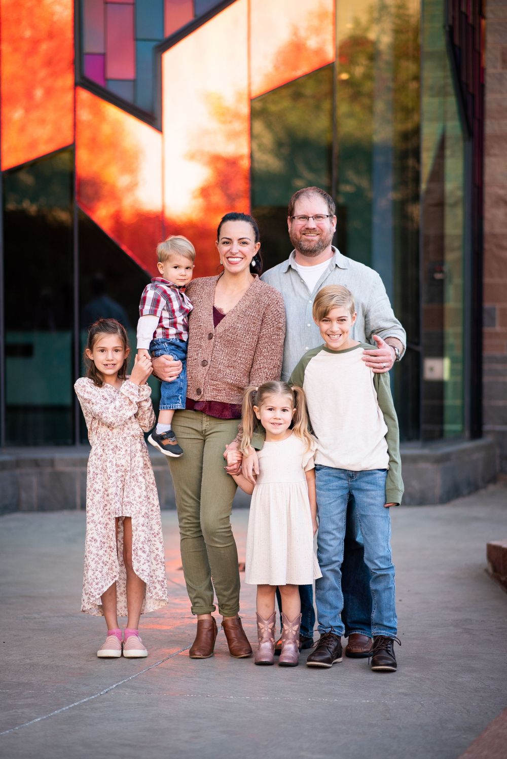 Family portrait of six people standing in front of a colorful modern architectural wall.