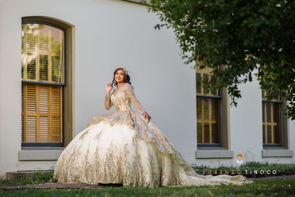 Ornate gold and white quinceañera dress with full skirt shown against classic architecture.