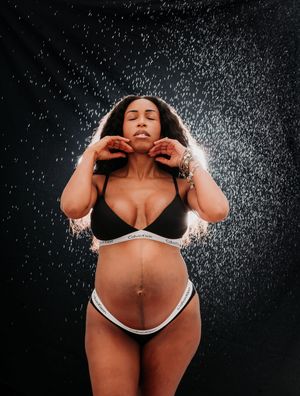 Artistic water spray photography series showing silhouetted figure in black lingerie against dark background. Maternity