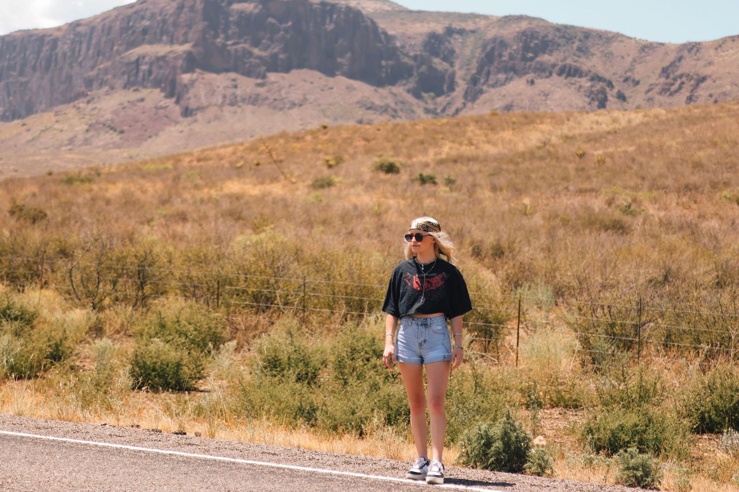 Scenic desert mountain landscape with figure hiking along empty road.
