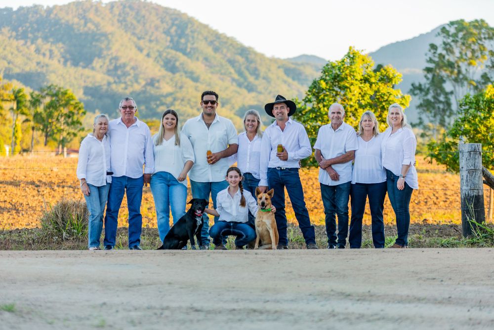 A group in white shirts and jeans poses together with their dog against a scenic mountain backdrop.