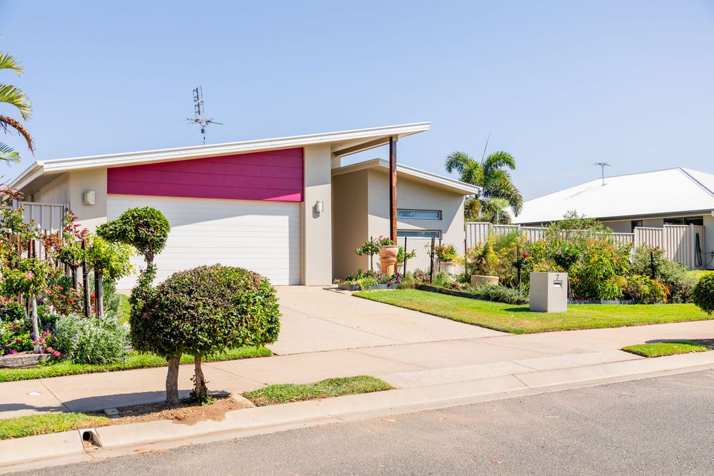 Modern suburban house with pink accent wall and landscaped tropical garden.