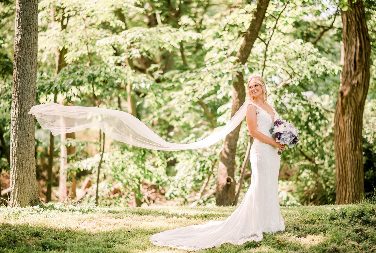 Flowing wedding veil catching the breeze in a sunlit forest setting. Indianapolis, Indiana. Angela Hartwig Photography.