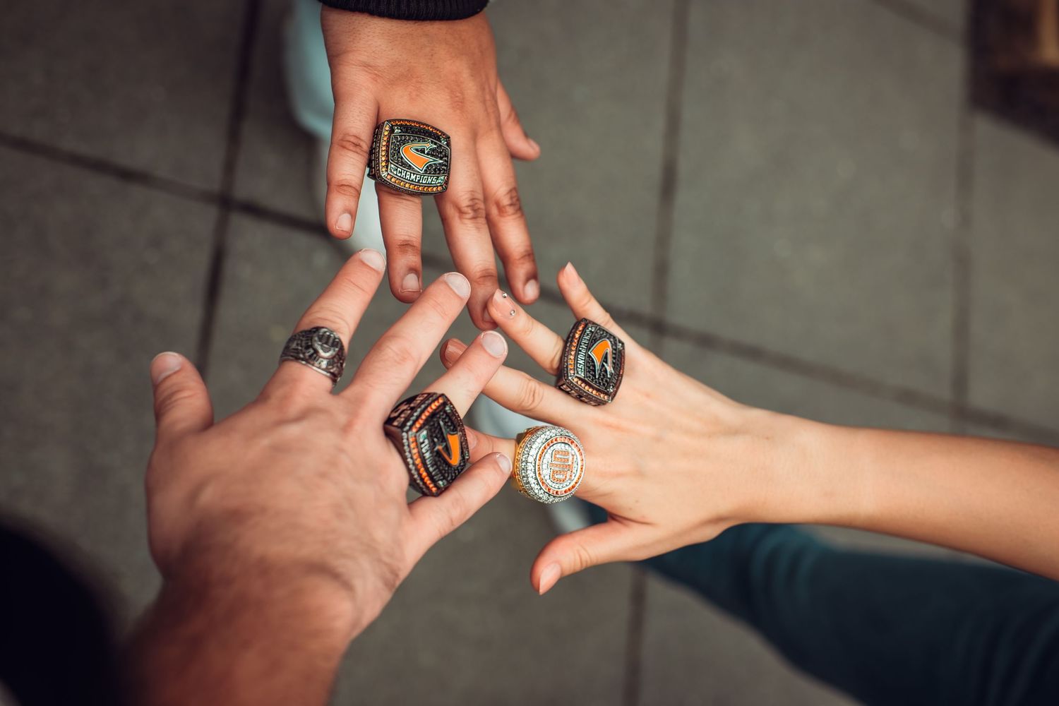 Multiple hands coming together showing off championship or class rings.