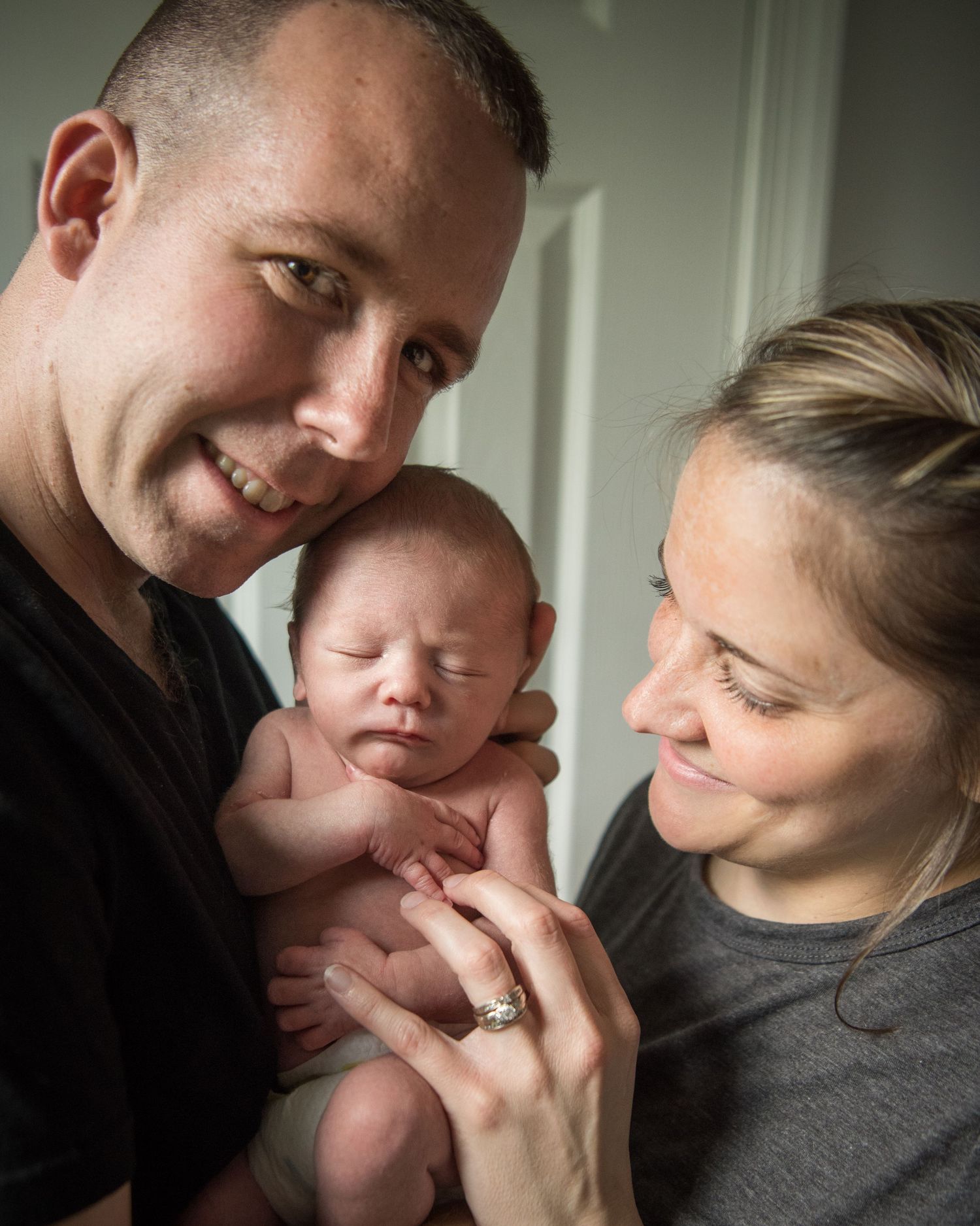 A newborn baby being lovingly cradled and admired by their parents in a tender family moment.