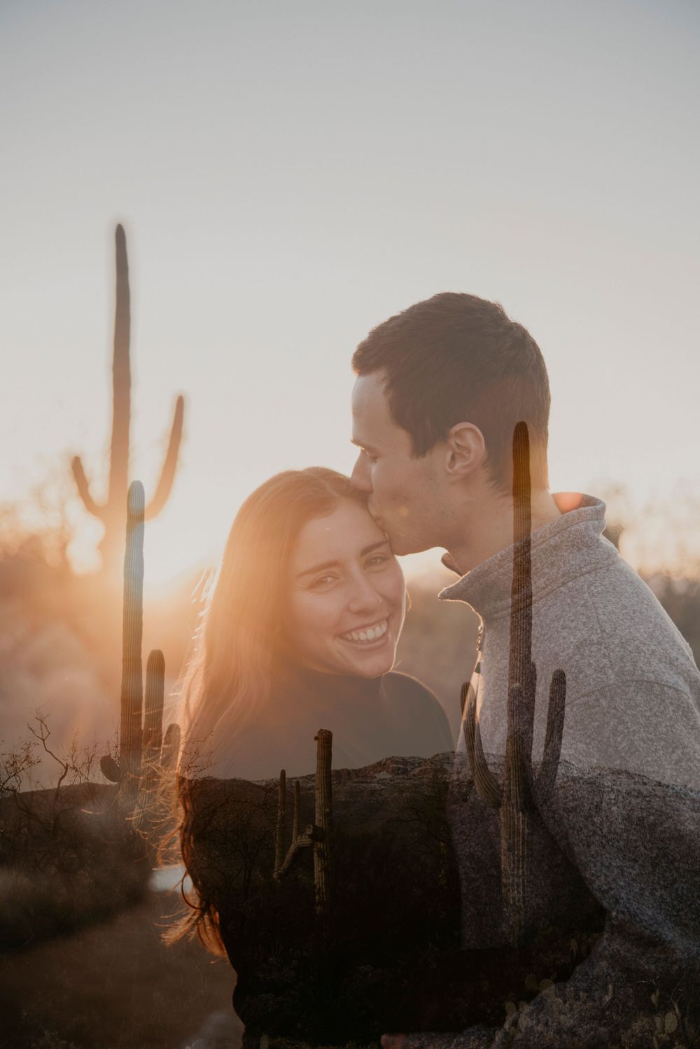 Silhouettes of a couple against desert cacti during golden hour.