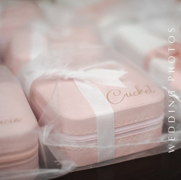 Pink wedding favor boxes tied with white ribbons arranged in soft focus.